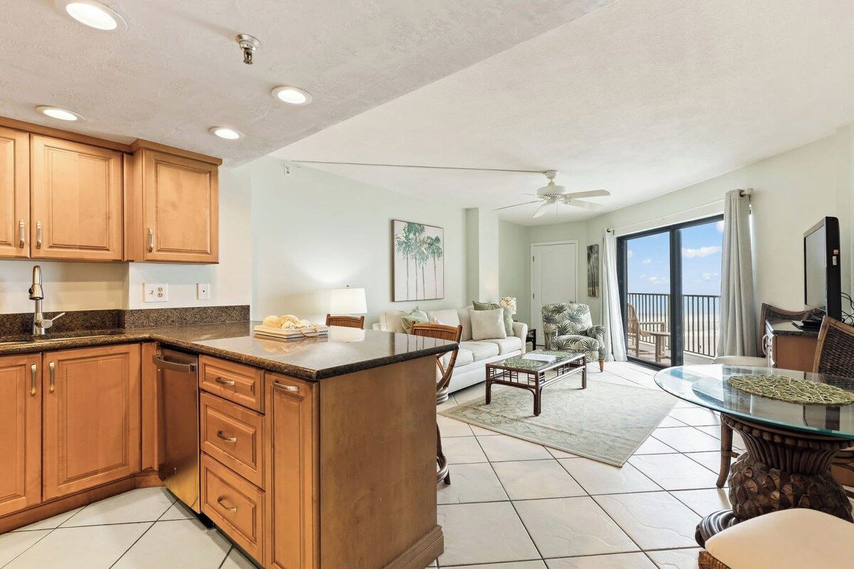Amplia sala de estar con cocina, mesa de comedor y un balcón con vistas.