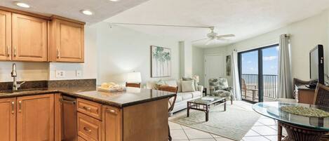 Amplia sala de estar con cocina, mesa de comedor y un balcón con vistas.