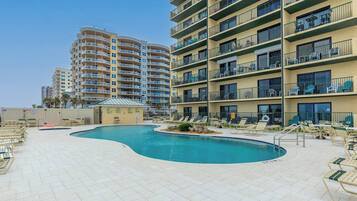A pool area with lounge chairs and a small pool, surrounded by multi-story buildings with balconies.