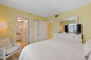 A bedroom with a bed, a television, a dresser, and a chair. - Breathtaking Views, Heated Pool & Beach Access! (Daytona Beach Shores)