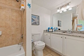 Un baño con bañera, inodoro y tocador con lavabo.