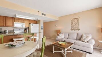 A compact living space with a kitchenette, a dining area, and a seating area with a sofa and a coffee table.