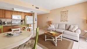 A compact living space with a kitchenette, a dining area, and a seating area with a sofa and a coffee table. - Ocean Front Condo w/ Amazing Views, Pool & Hot Tub (Daytona Beach Shores)