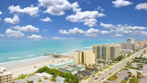 Un paysage urbain côtier avec une plage, des immeubles de grande hauteur et un ciel dégagé.