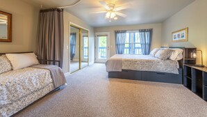 A bedroom with two beds, a ceiling fan, a nightstand, and a window with curtains. - 28 Lodge 1 Bedroom Condo by RedAwning (Hood River)