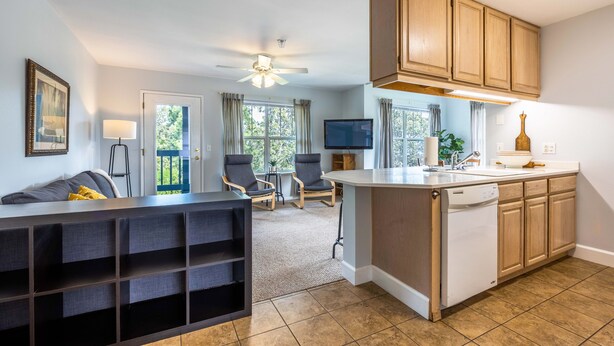 A modern kitchen with wooden cabinets, a built-in island, and a dining area with chairs. - 28 Lodge 1 Bedroom Condo by RedAwning (Hood River)