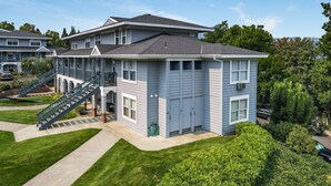 A two-story residential building with a covered porch and a staircase leading to the upper floor. - 28 Lodge 1 Bedroom Condo by RedAwning (Hood River)