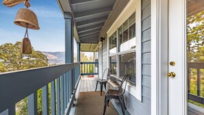 A porch with a wooden railing, two chairs, a doormat, and a bell. - 28 Lodge 1 Bedroom Condo by RedAwning (Hood River)
