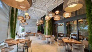 A modern restaurant with hexagonal patterned flooring, wooden tables and chairs, and hanging pendant lights.