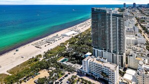 A high-rise hotel with a beach view, multiple floors, and a parking area.