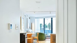A modern living room with a dining area, large windows, and a view of the outside.
