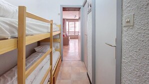 A narrow hallway with bunk beds on one side and a door on the other.