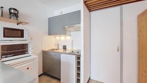 A compact kitchen with a microwave, oven, sink, and dishwasher.