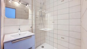 A modern bathroom with a white sink, mirror, and shower area.