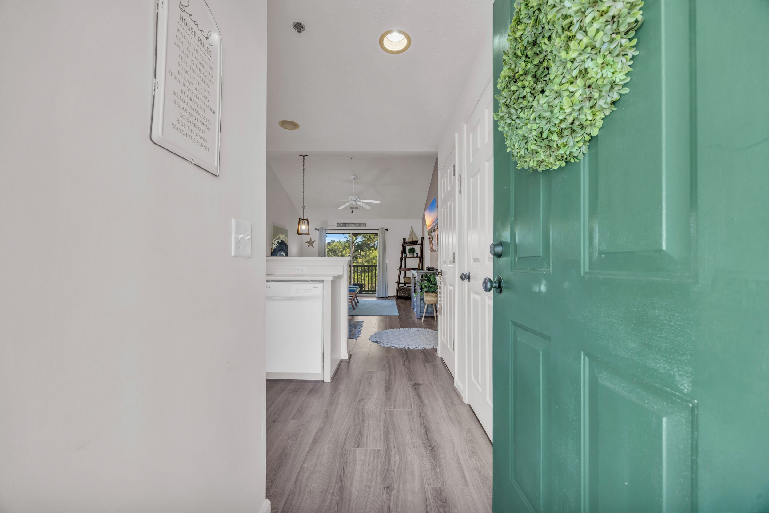 A hallway with a green door, white walls, and a ceiling fan.