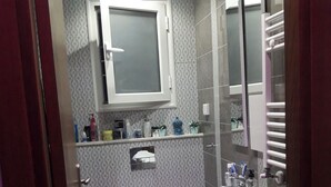 Ein kleines Badezimmer mit einem weißen Waschbecken, einer Toilette, einer Dusche und einem Spiegel über dem Waschbecken.