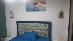 Ein Schlafzimmer mit einem Bett, zwei Nachttischen, einem Wandbild und zwei Wandleuchten.