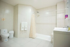 A bathroom with a toilet, a bathtub, and a shower curtain.
