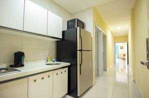 A kitchen with a refrigerator, a coffee maker, and a sink.