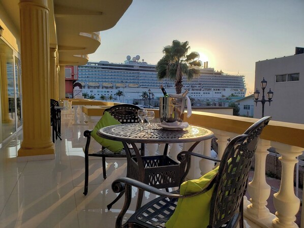 A balcony with a table, chairs, and a champagne bucket.