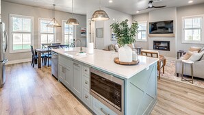 Uma cozinha espaçosa com uma ilha grande, luminárias pendentes e forno embutido.