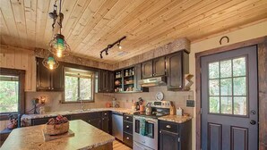 A kitchen with wooden cabinets, a granite countertop, a stove, and a large window.