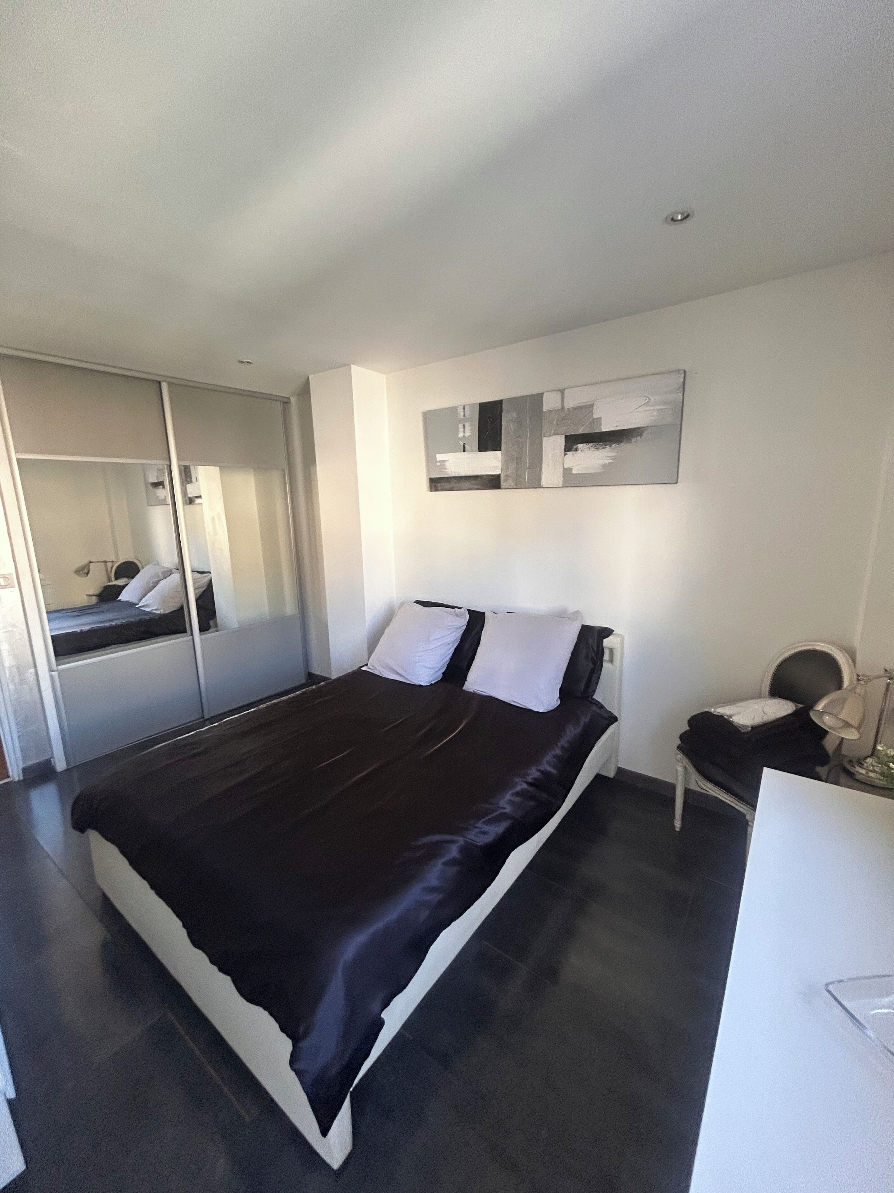 A modern bedroom with a bed, bedside table, and a mirror.