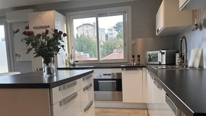 Ett modernt kök med vita skåp, en svart bänkskiva och ett fönster med utsikt över ett bostadsområde.