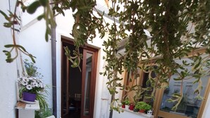 A small outdoor patio with a white table and blue chairs, surrounded by potted plants and a patterned rug. - Central Private home,  close to all you need in Viareggio (Viareggio)