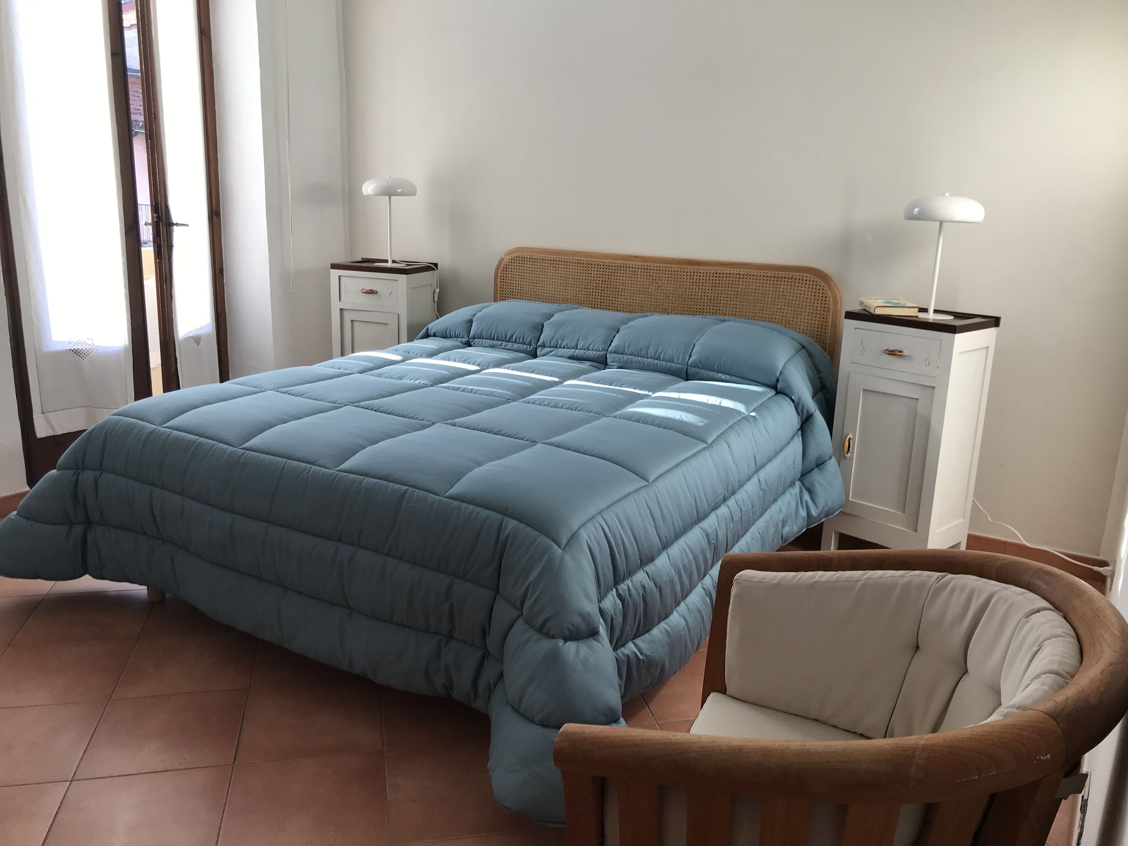 Ein Schlafzimmer mit einem großen Bett, zwei Nachttischen, einem Sessel und einem Kleiderschrank.
