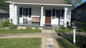 A single-story house with a porch, a mailbox, and a small garden area. - Cozy house on a quiet street (Bedford)