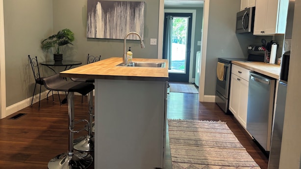 A modern kitchen with a central island, stainless steel appliances, and a view to the outdoors. - Cozy house on a quiet street (Bedford)