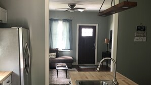 A compact kitchen with a built-in sink, a refrigerator, and a ceiling fan. - Cozy house on a quiet street (Bedford)
