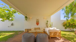 An outdoor living area with a wooden deck, a sofa, a daybed, and two bean bags.