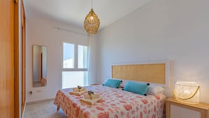 A bedroom with a bed, bedside table, lamp, and window.