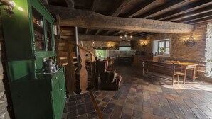A rustic kitchen with wooden beams, a green cabinet, and a tiled floor.