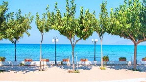 A seaside promenade with trees, benches, and street lamps. - Georgioupolis Blue Villa Private Pool (Georgioupoli)