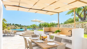 Un área de comedor al aire libre con piscina, escalones de piedra y vistas del paisaje.