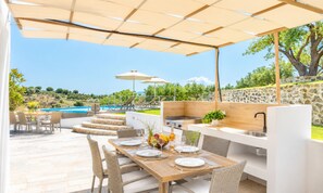 An outdoor dining area with a pool, stone steps, and a view of the landscape. - Georgioupolis Blue Villa Private Pool (Georgioupoli)