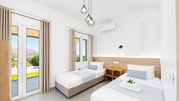 Una habitación de hotel moderna con cama, mesita de noche y una ventana con cortinas.