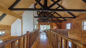 A wooden interior with a central staircase, wooden railings, and large windows.