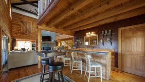 A rustic cabin interior with a wooden dining area, bar, and seating.