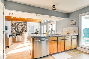 A modern kitchen with a central island, wooden cabinets, and a stone backsplash.