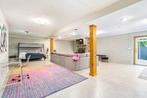 Een ruime woonkamer met een bed, bank en open haard.