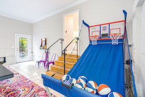 A home basketball court with a blue slide, a basketball hoop, and a few basketballs.