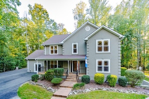 A two-story house with a porch, a driveway, and well-maintained landscaping.