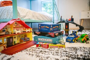 Ein Spielbereich für Kinder mit einer Puppenstube, Gesellschaftsspielen und Spielzeugfahrzeugen.