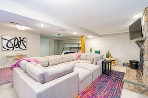 Ein modernes Wohnzimmer mit einem Ecksofa, einem Kamin und einem farbenfrohen Teppich.