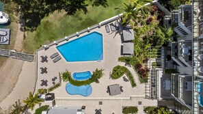 A rooftop pool area with a large rectangular pool, smaller circular pool, and lounge chairs.