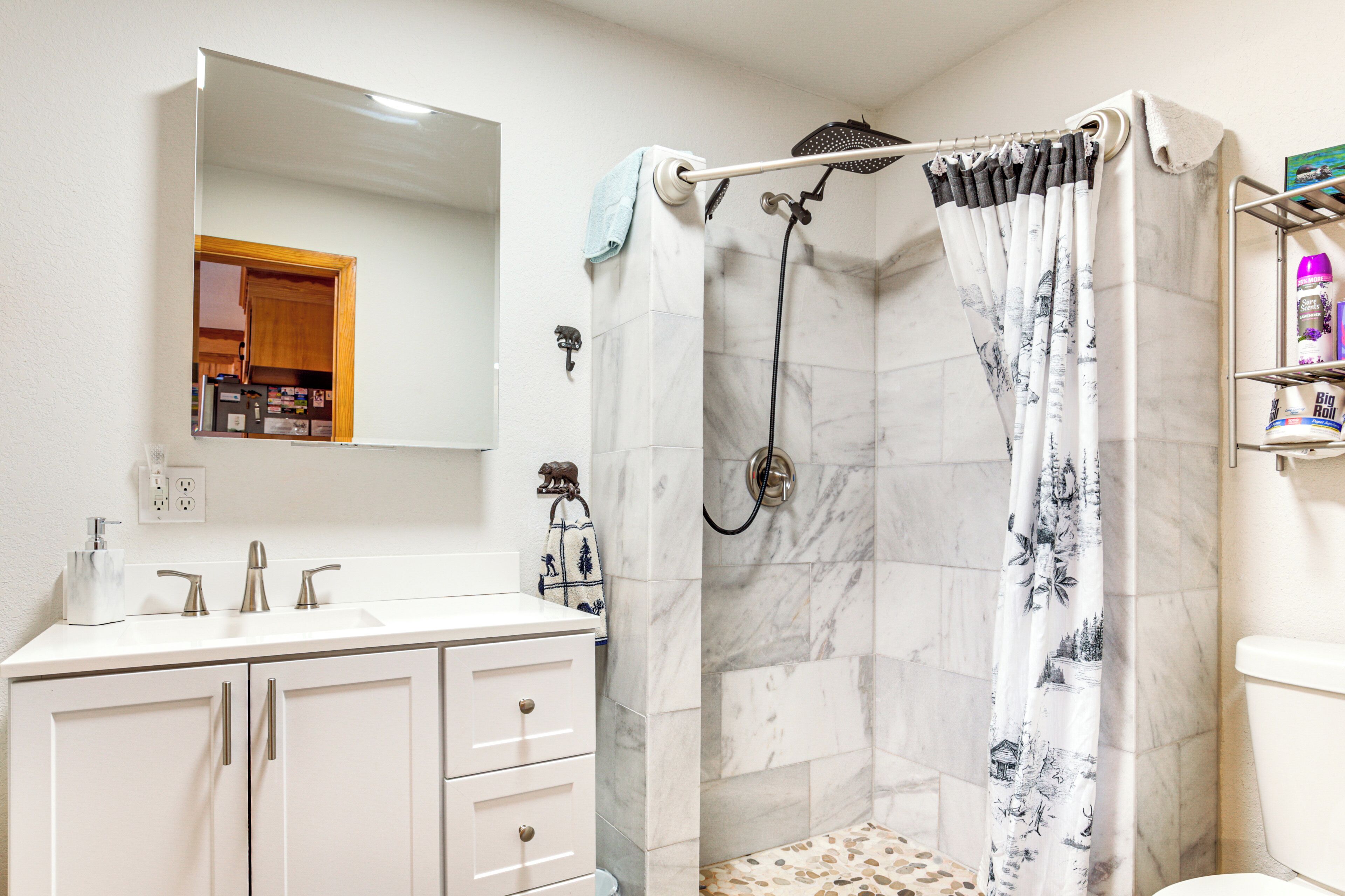 A bathroom with a shower, a sink with a mirror, and a toilet.